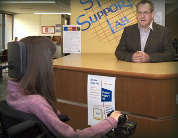 Student in wheelchair talking to college administrator.