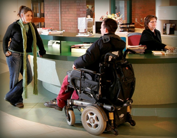 Student in wheel chair in college lobby.