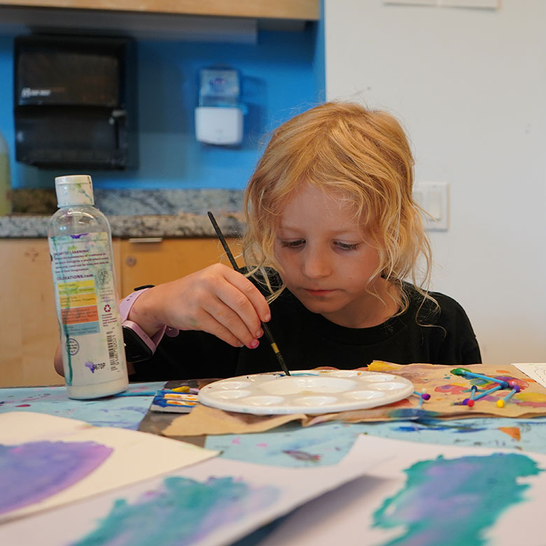 an image of a young girl painting at a table
