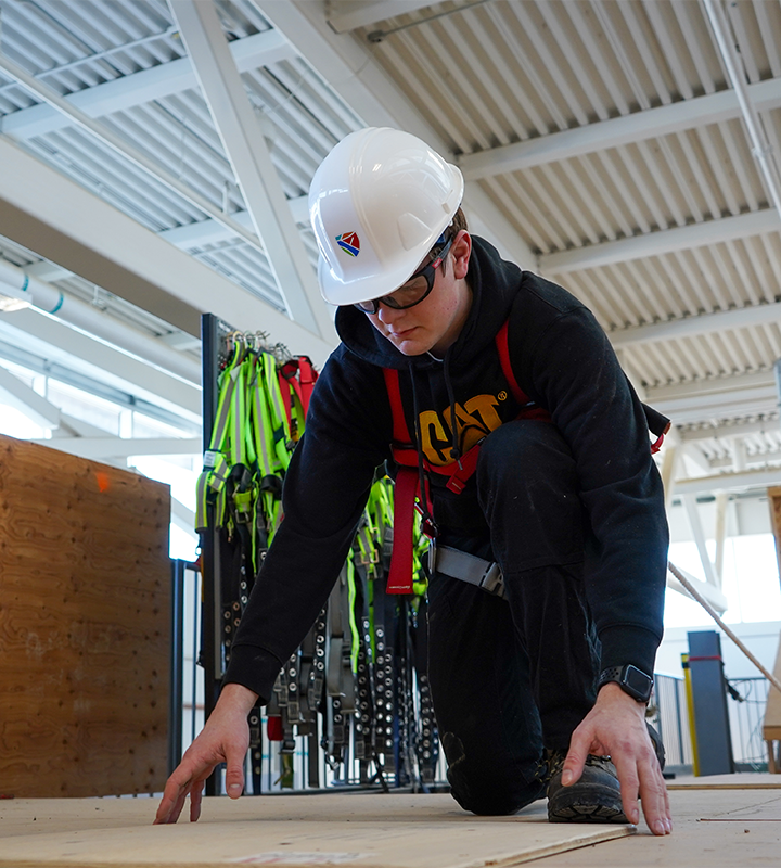 Student laying plywood during working at heights certification course at Fleming College