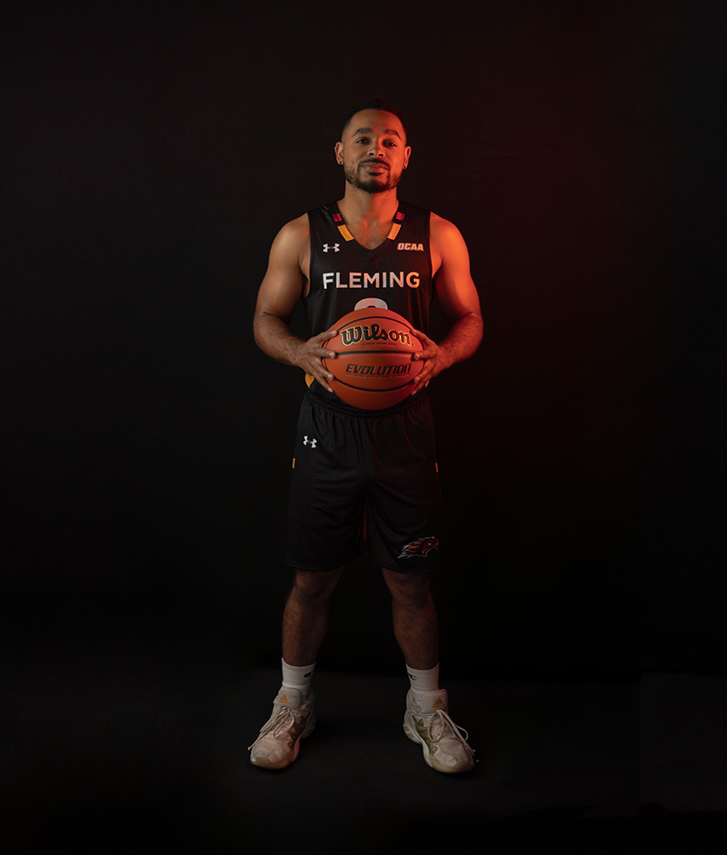 Male basketball player holding a basketball and wearing a Fleming Phoenix uniform.