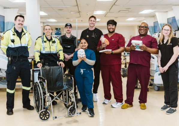 A group of students in the School of Applied Health and Community Services wearing nursing and paramedic uniforms.