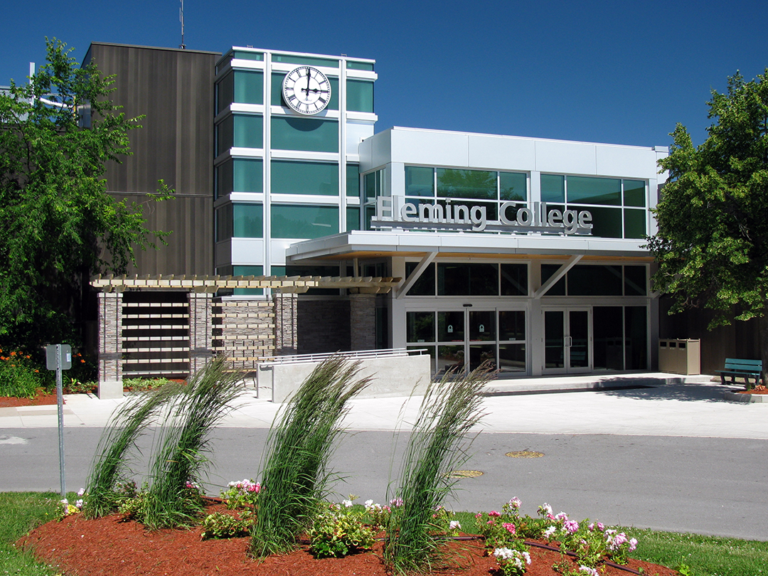 the main entrance of fleming college shows the college name in large metal letters above 2 sets of large double sliding doors.